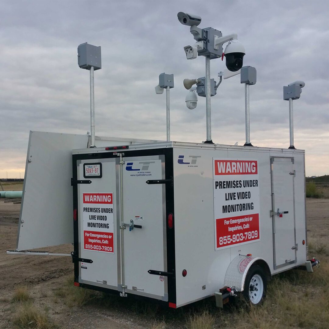 Mobile surveillance unit with multiple cameras and warning signs on a plain background.