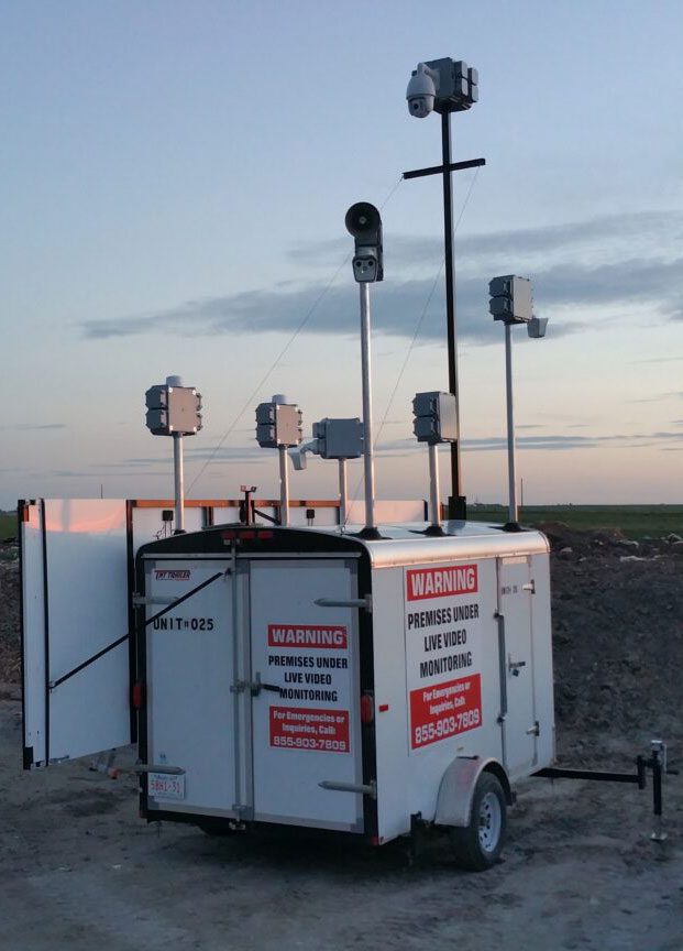 Mobile surveillance unit with multiple cameras and warning signs under the twilight sky.