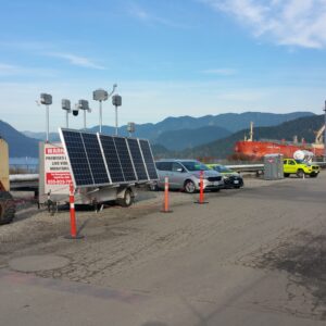 Solar panels next to a parking lot with mountains in the background.