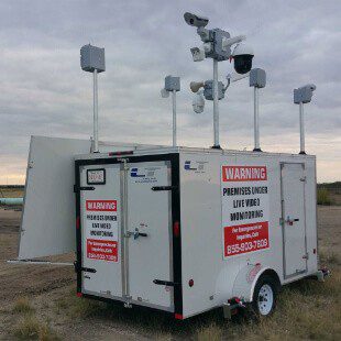 Mobile surveillance unit with multiple cameras and sensors, and warning signs indicating live video monitoring.