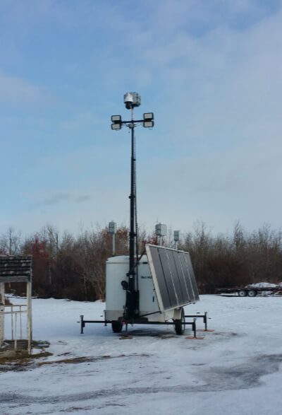 Mobile light tower with generator on a snowy field.