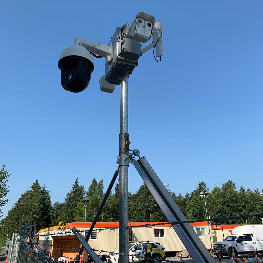 Surveillance cameras mounted on a pole with clear skies in the background.