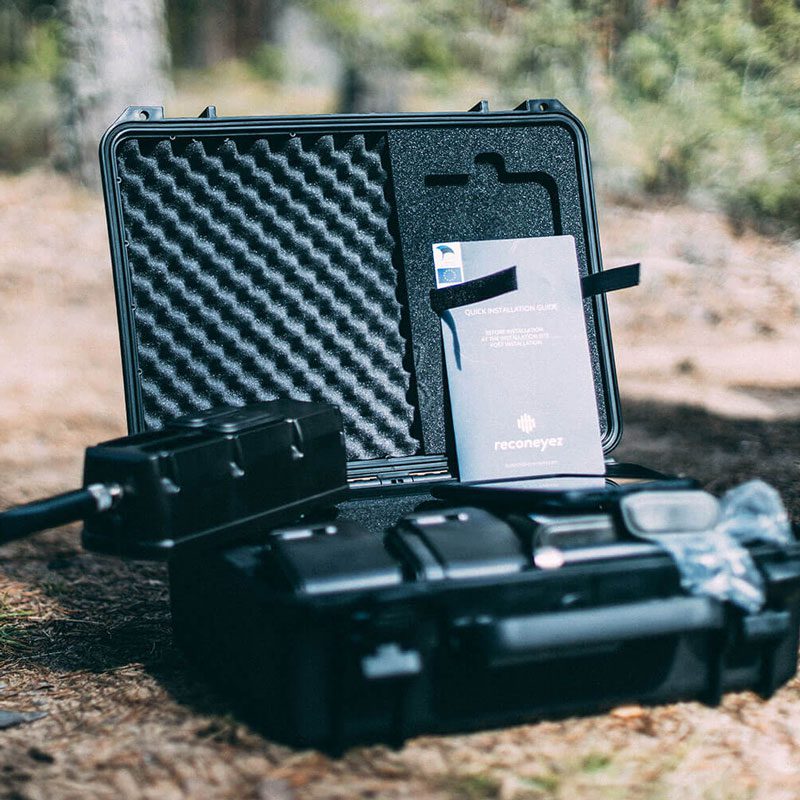 A drone and its components neatly packed into a protective carry case with foam lining, set against a natural outdoor backdrop.