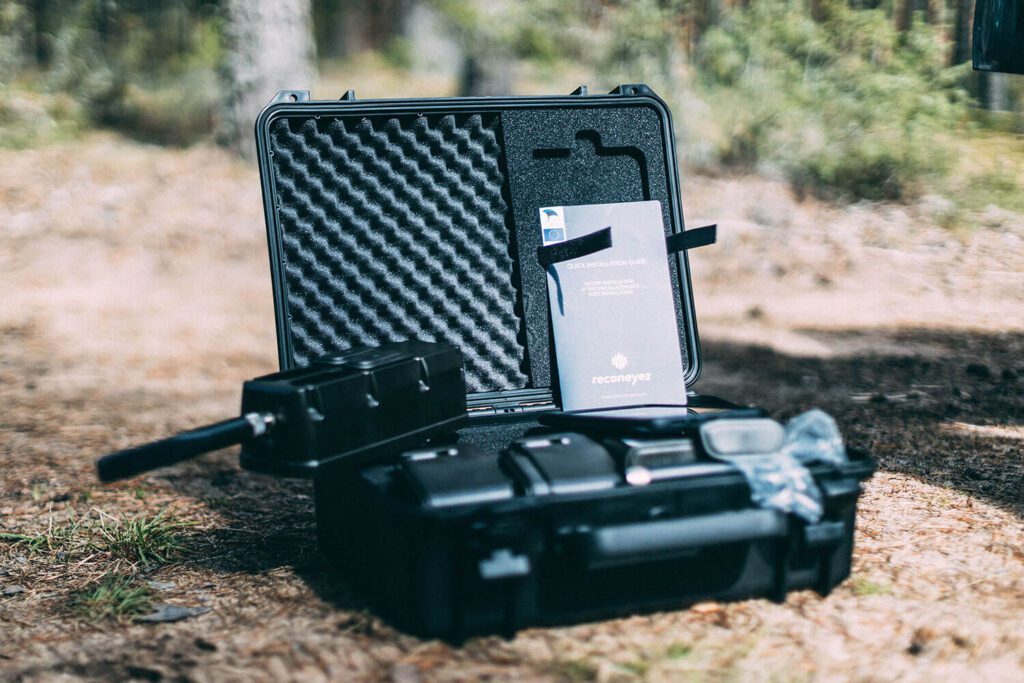 A drone with its accessories and packaging placed on the ground outdoors.