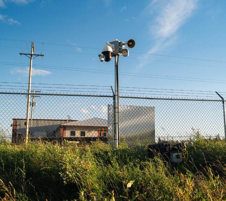 Security cameras mounted above a chain-link fence at a secured job site