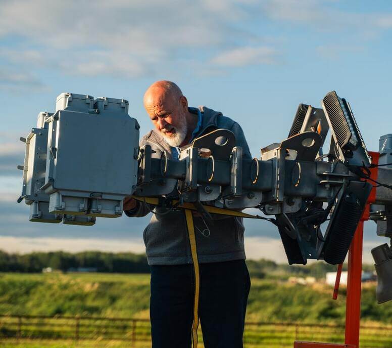 Technician inspecting a mounted surveillance camera system in an outdoor worksite